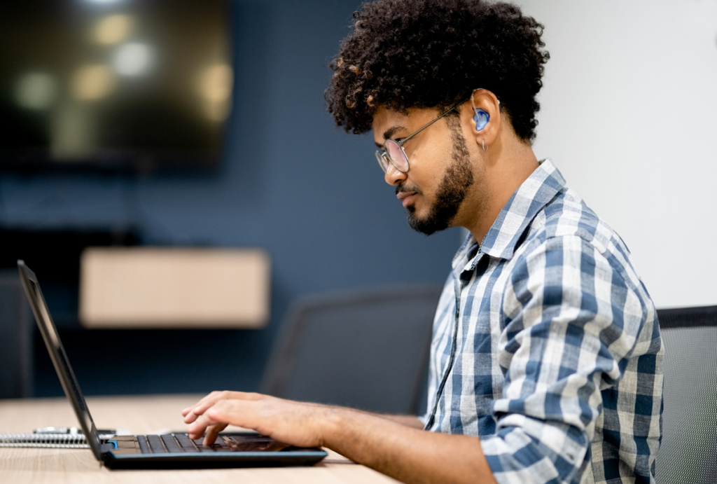 Man with hearing aid using a laptop