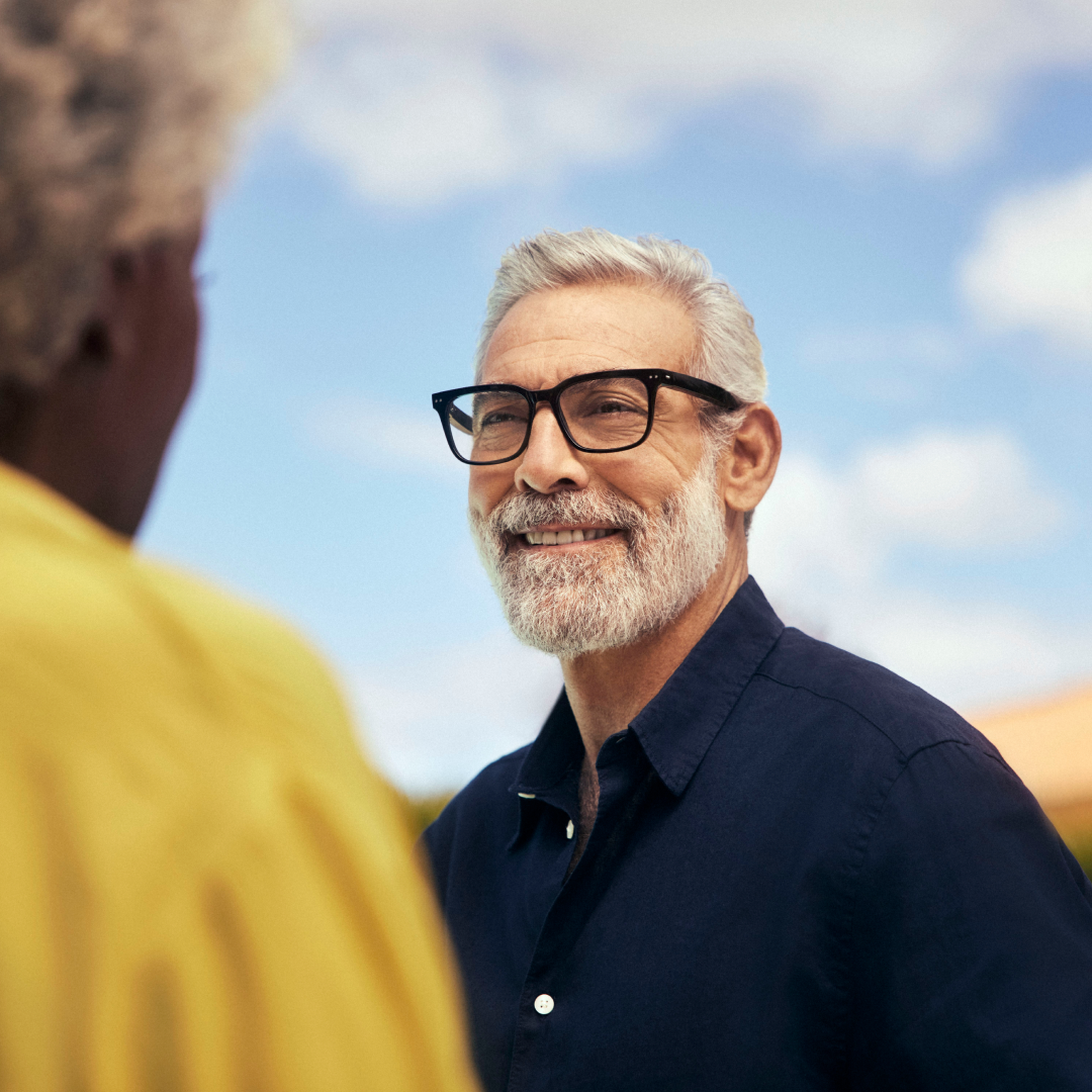 a senior man wearing Nuance Audio Glasses speaking with their partner outdoors